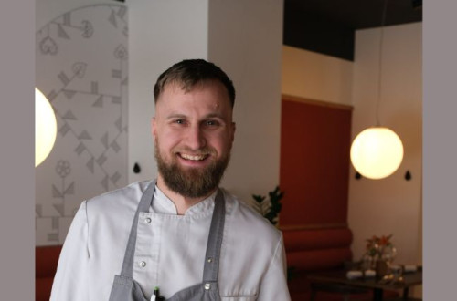 Smiling chef in a restaurant, in a white shirt and grey apron