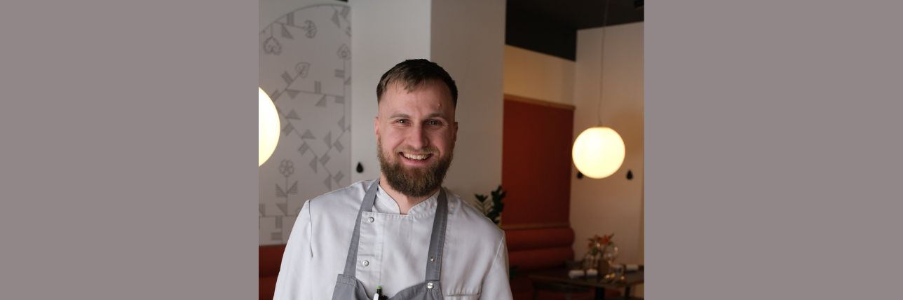 Smiling chef in a restaurant, in a white shirt and grey apron