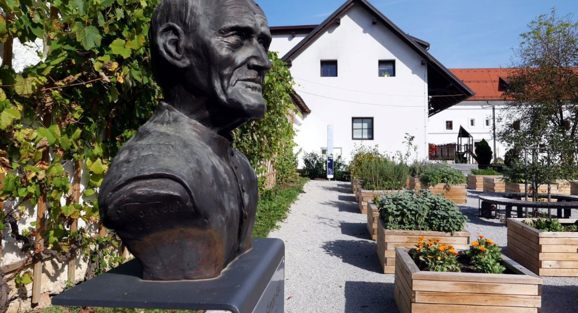 A bust of a man near a garden.