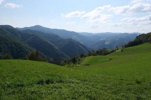 A landscape with wide meadows and forested hills.