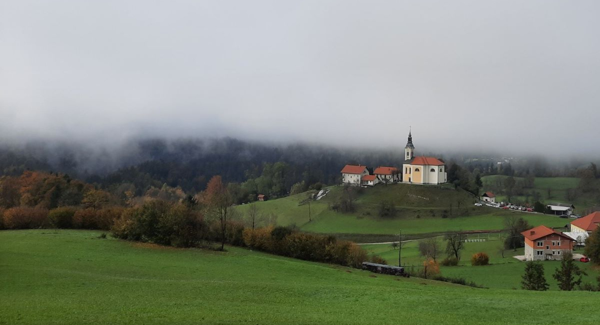 A hilly landscape with a village and a small church.