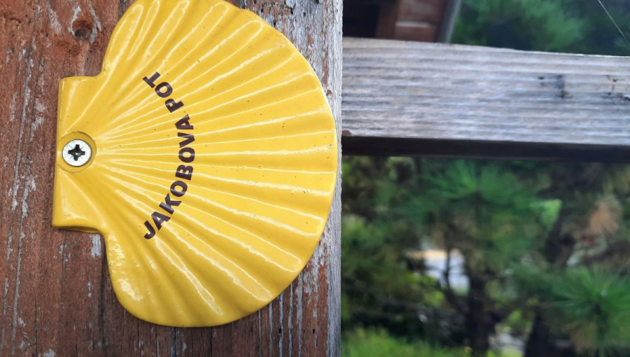 A trail marker in the shape of a yellow scallop shell with the inscription 'Way of St. James'.