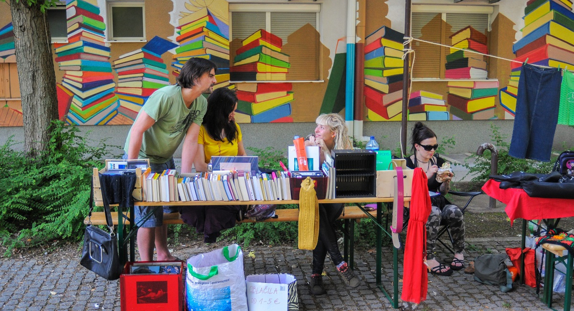 A wall painted with books, with a book stall in the foreground.