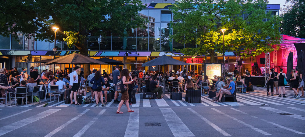 A group of people sitting at an evening event in front of a building.