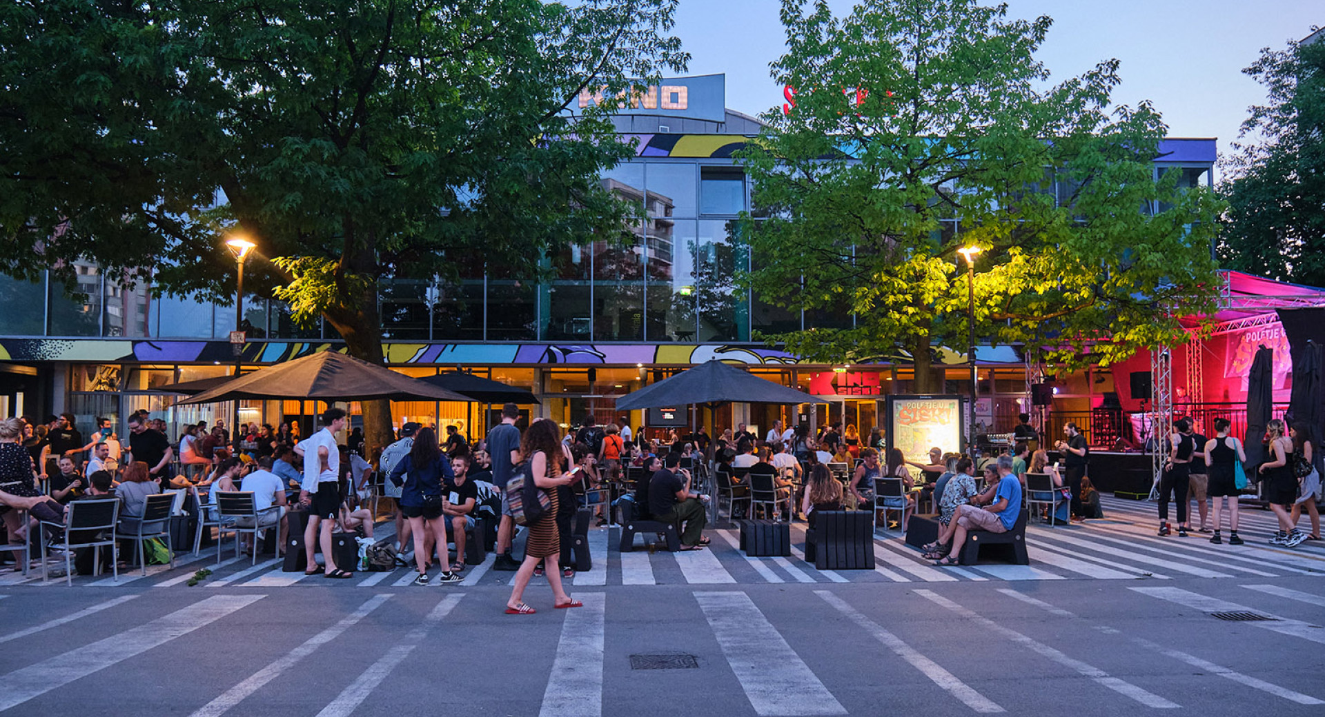 A group of people sitting at an evening event in front of a building.