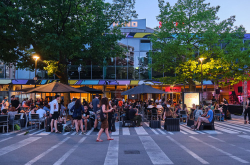 A group of people sitting at an evening event in front of a building.