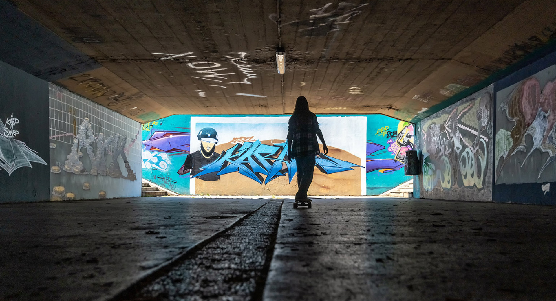 Graffiti on the Walls of the Underpass. A Girl Skateboards.