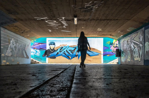 Graffiti on the Walls of the Underpass. A Girl Skateboards.