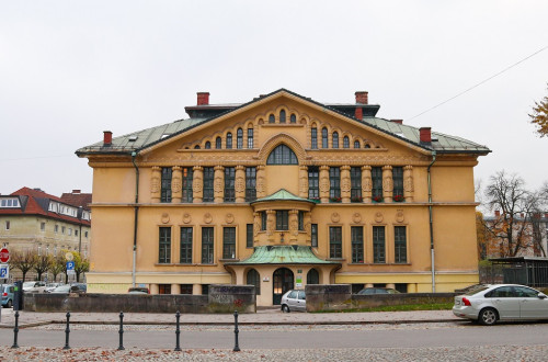 A large yellow building with numerous vertical windows and a regal entrance.