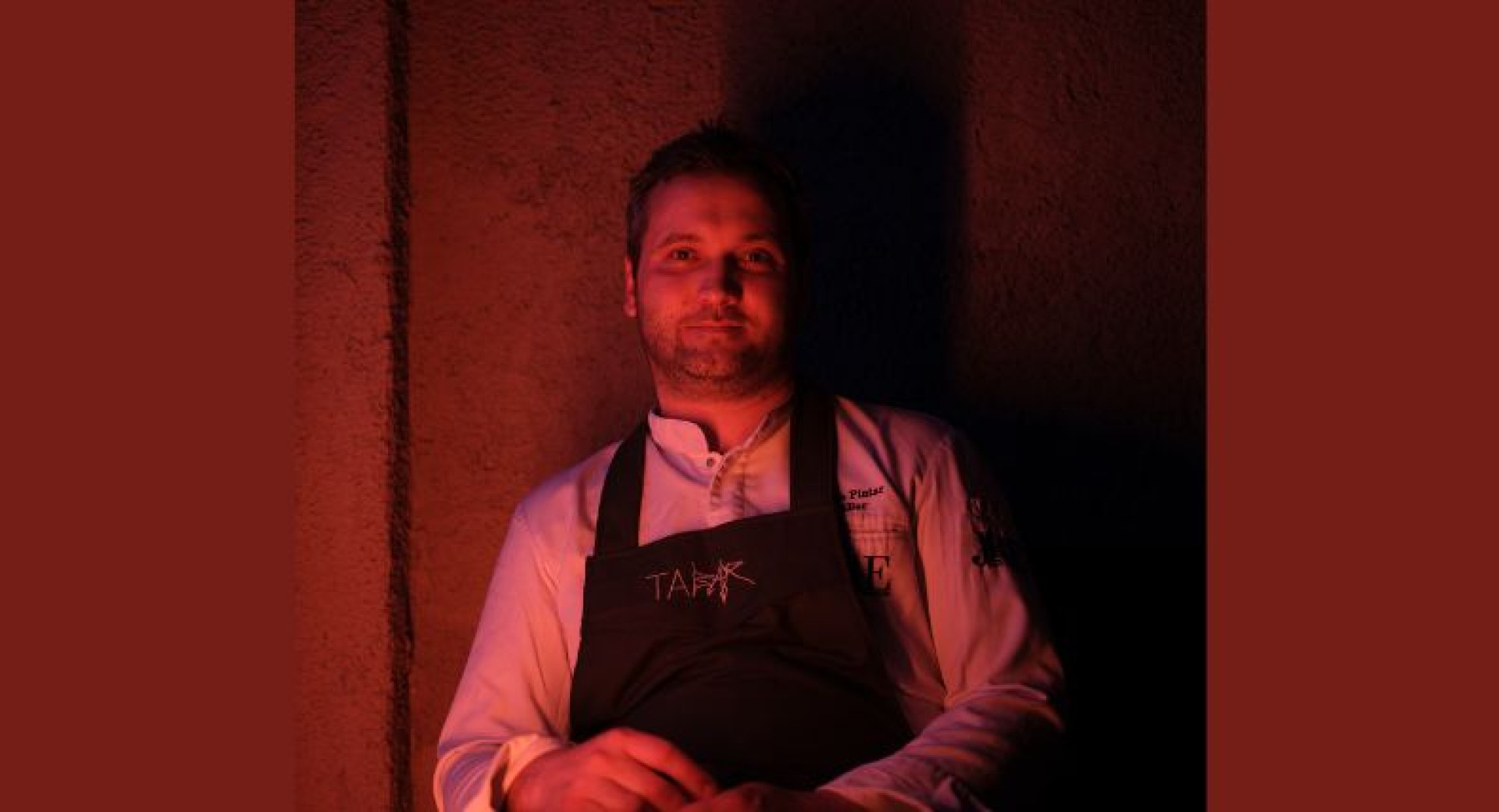 Man in a white shirt with a black apron, red lighting