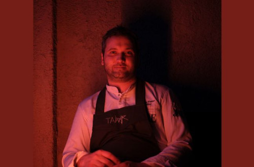 Man in a white shirt with a black apron, red lighting