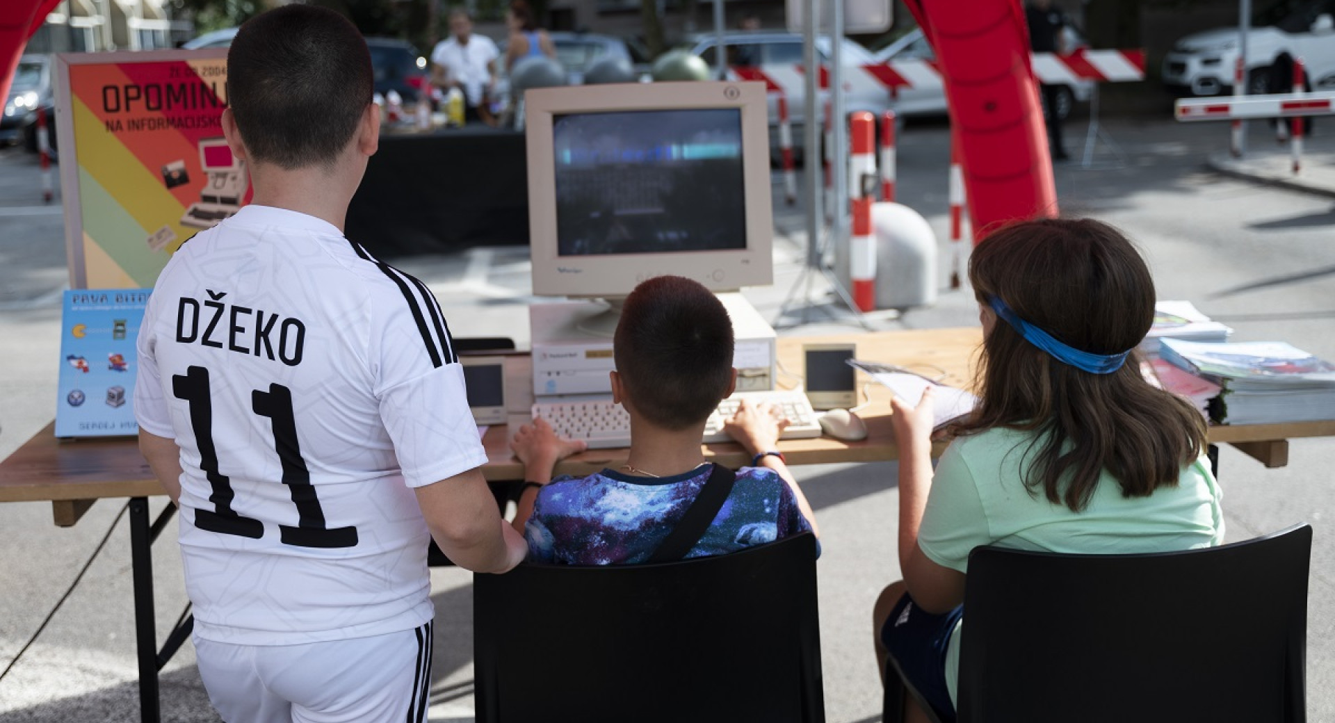 Three children are watching a computer while one child is playing a game.