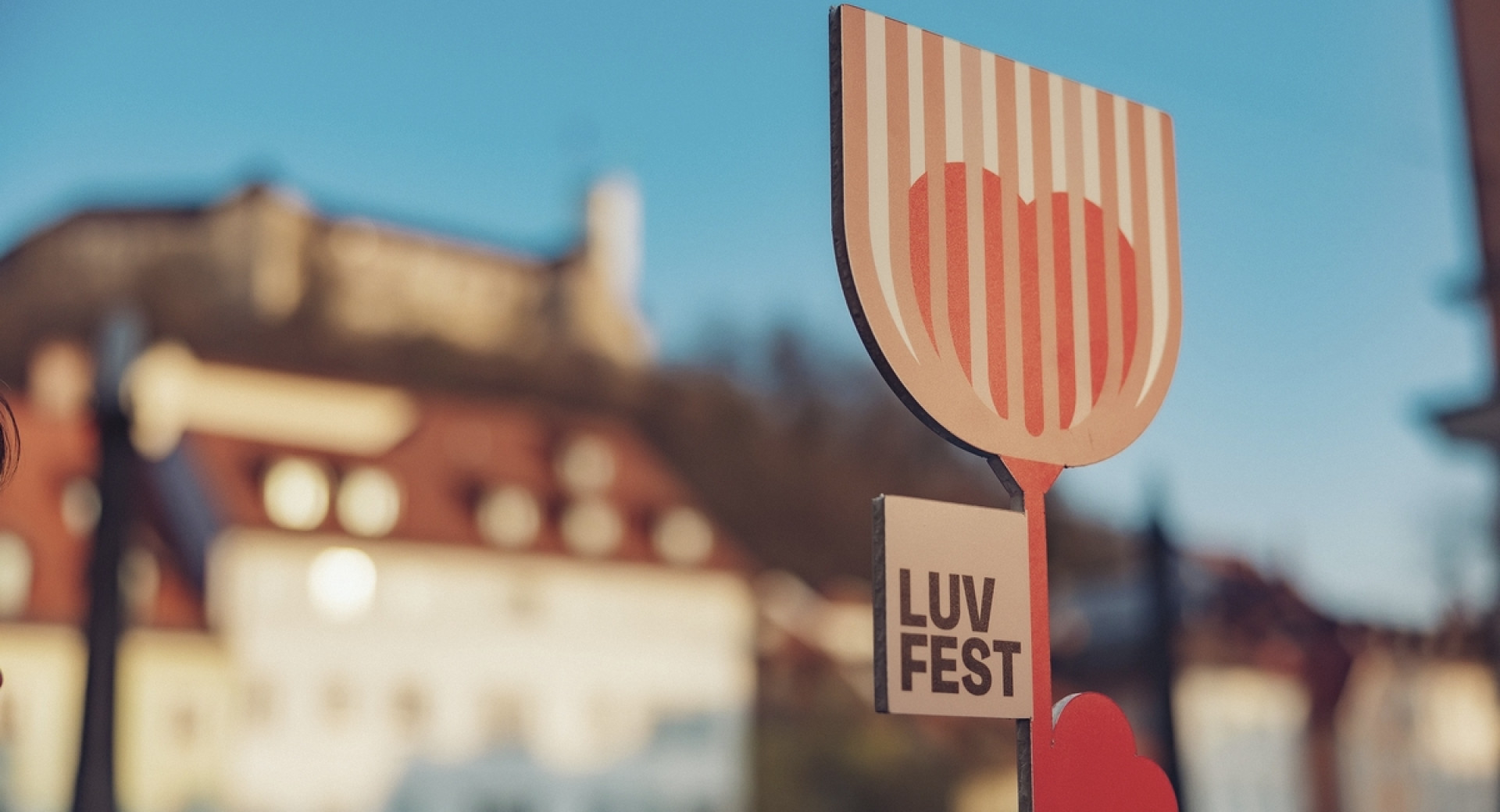 Lesena roža z napisom LUV fest, v ozadju grad