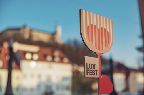 Lesena roža z napisom LUV fest, v ozadju grad