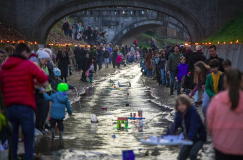 Množica ljudi spušča gregorčke po Gradaščici v Ljubljani.