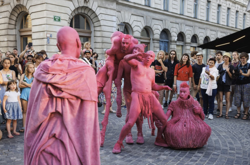 Skupina uličnih umetnikov, pobarvanih in oblečenih v roza barvo.