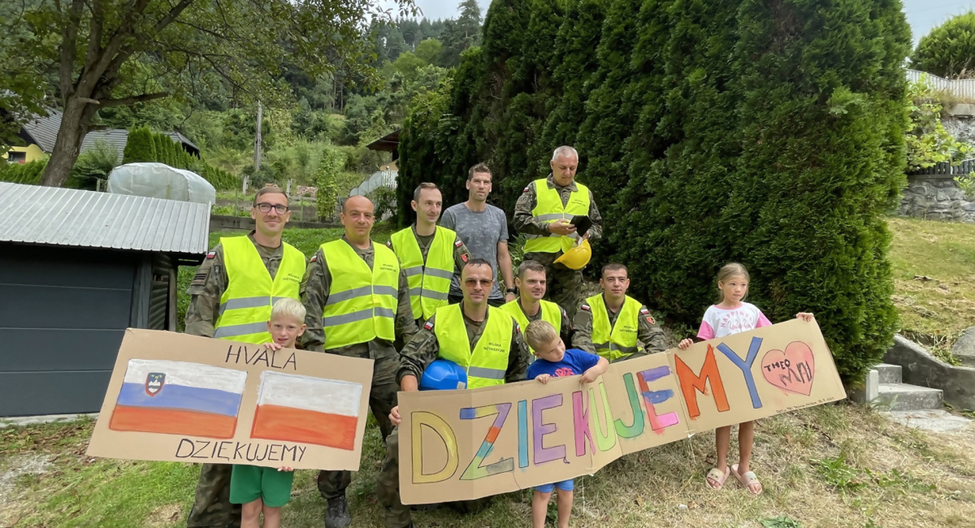 Skupina ljudi z rumenimi delovnimi brezrokavniki drži transparent.