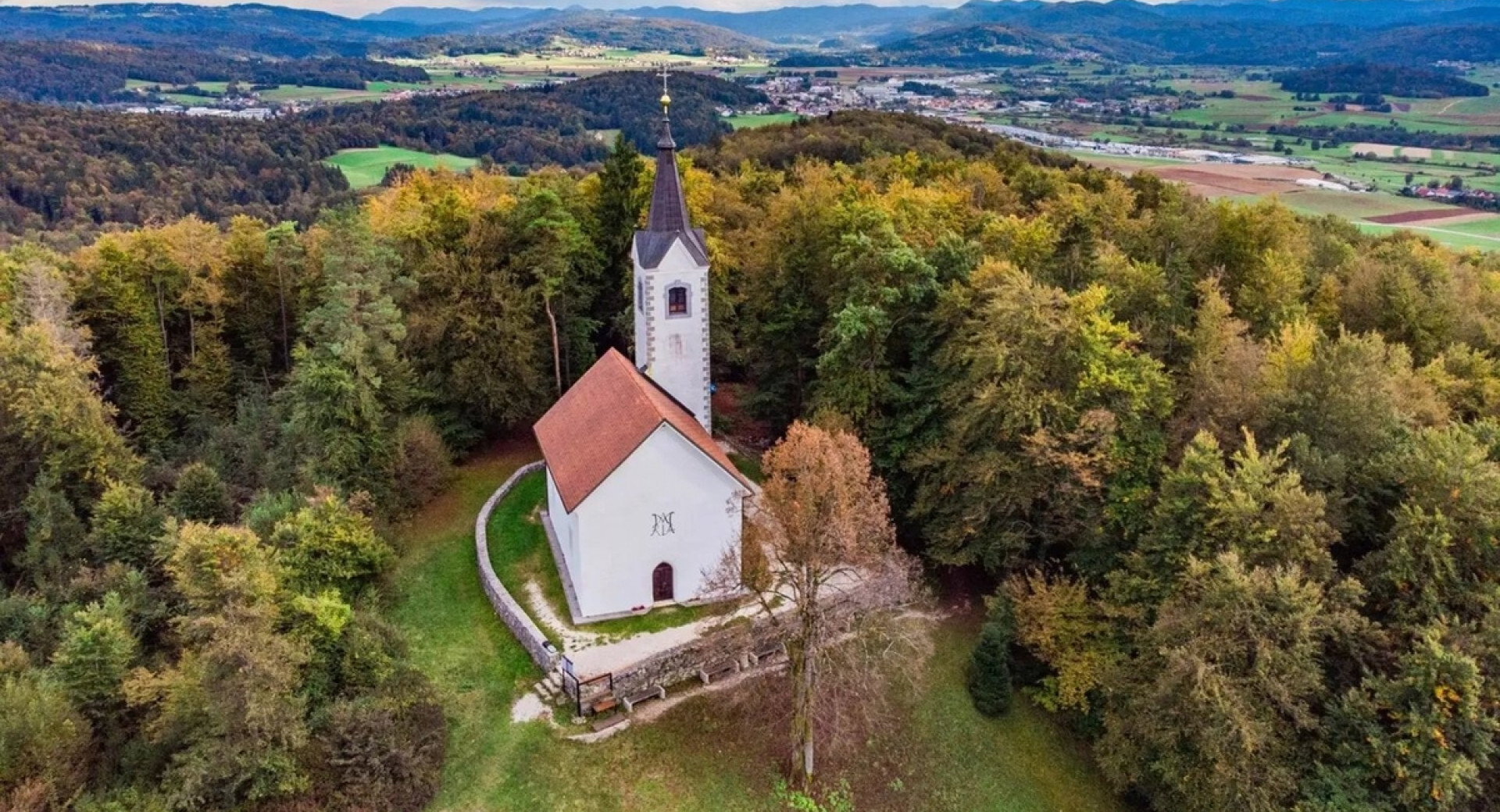 Cerkev na hribčku sredi gozda.