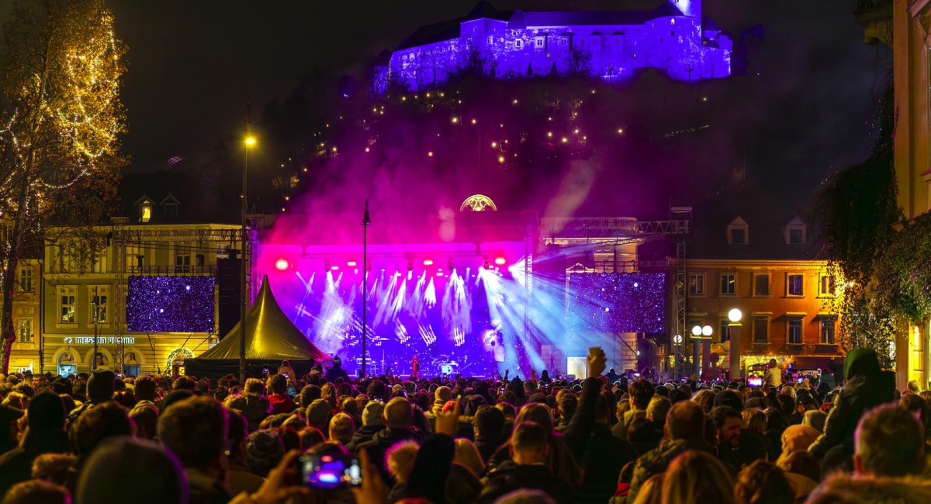 Koncert na prostem, v ozadju na griču grad.