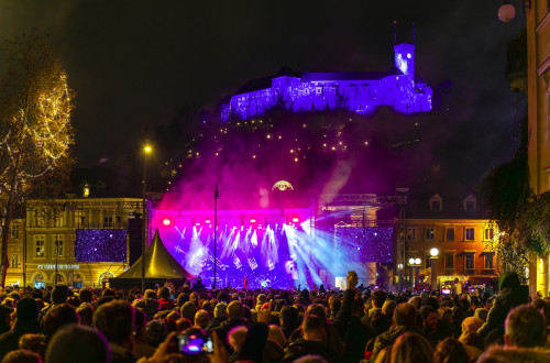 Koncert na prostem, v ozadju na griču grad.