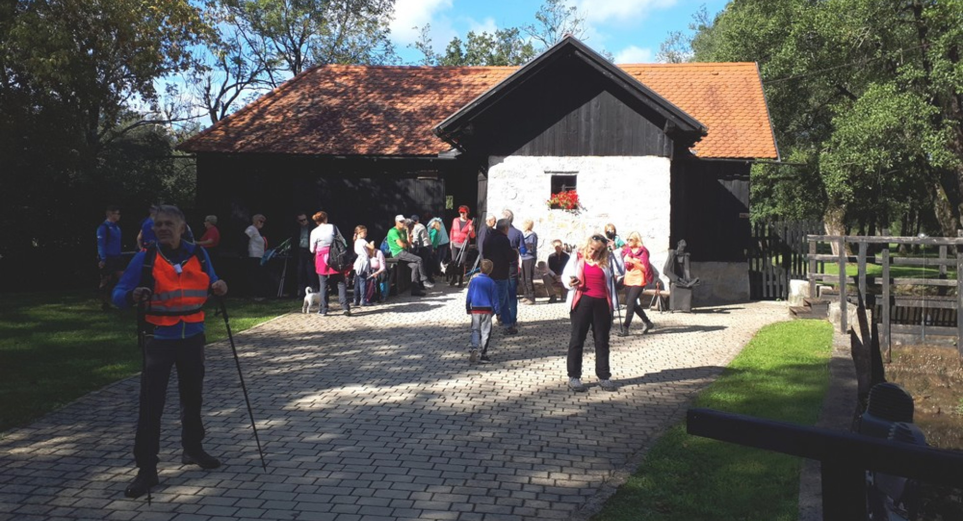 An old farmhouse with a white façade. People in sportswear in the courtyard.