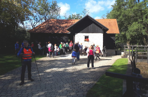 An old farmhouse with a white façade. People in sportswear in the courtyard.