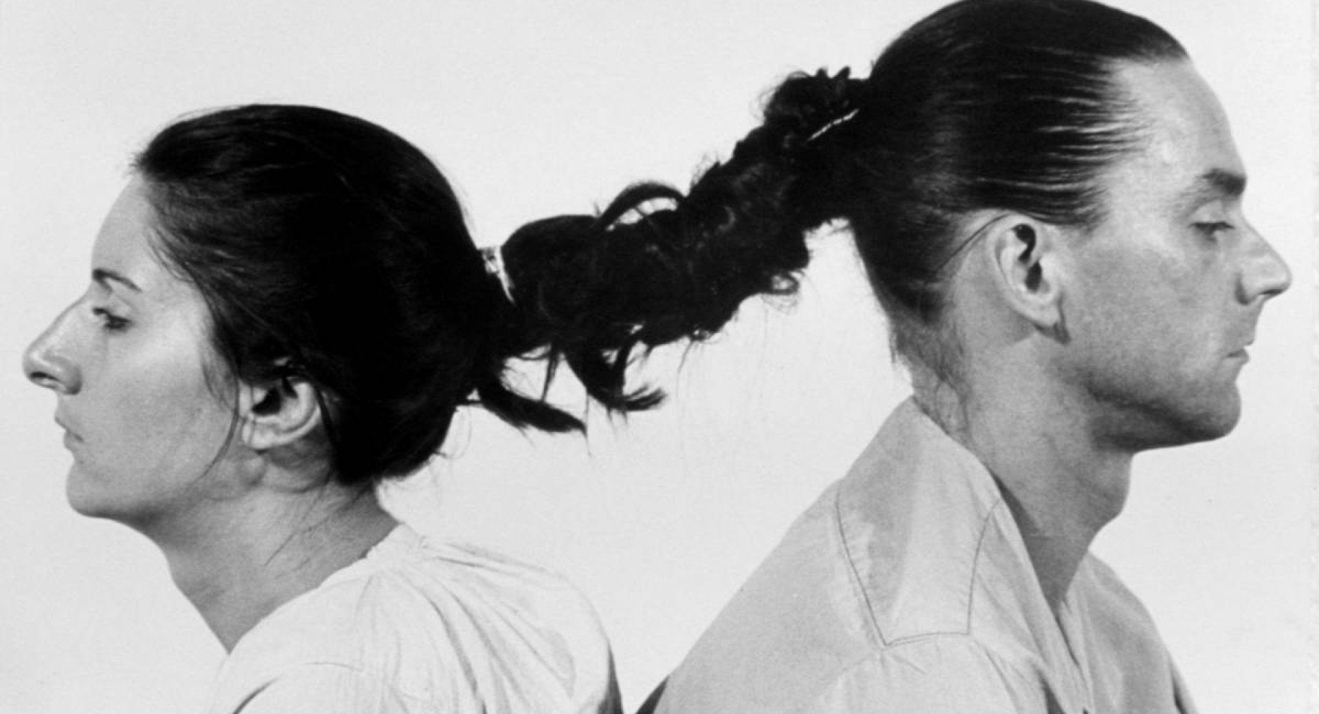 Man and woman photographed from the side with intertwined hair.