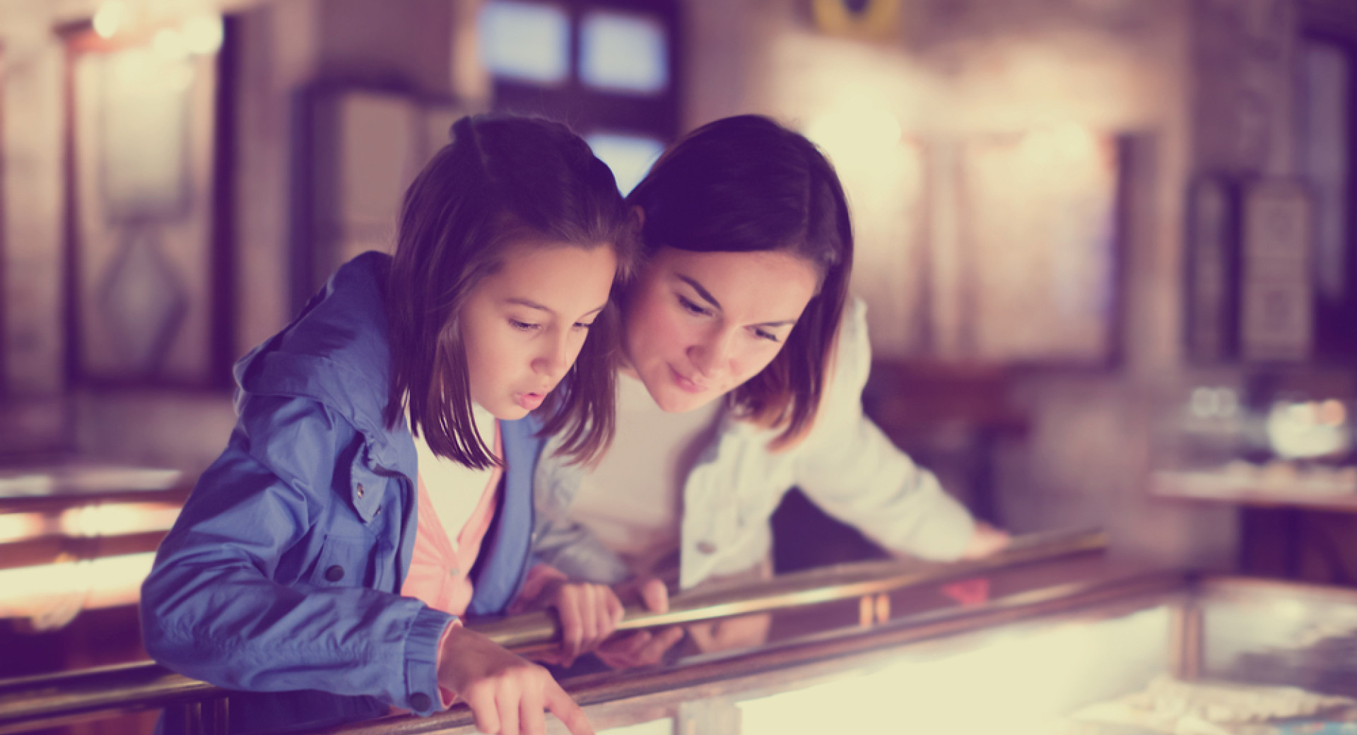 A mother and daughter are viewing the exhibition in the museum. The daughter is pointing out a part of the exhibition to her mother.