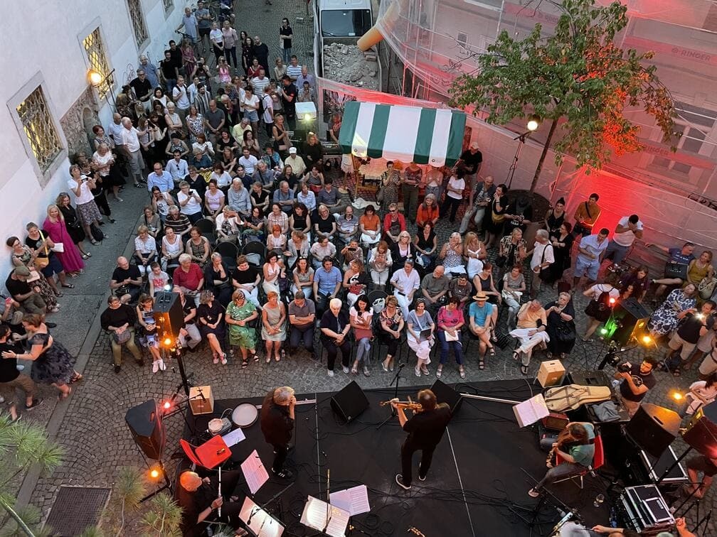 A bird's-eye view of a crowd of people on the street and a stage with performers.