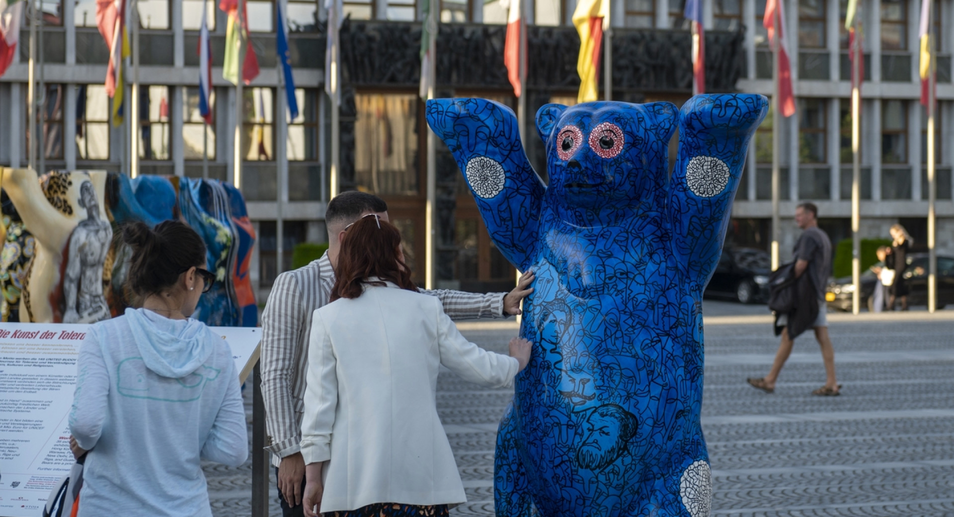 Modra skulptura medveda, ob njem obiskovalci.