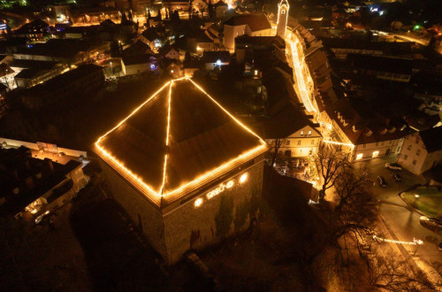 The house roof and city streets are decorated with festive lights.