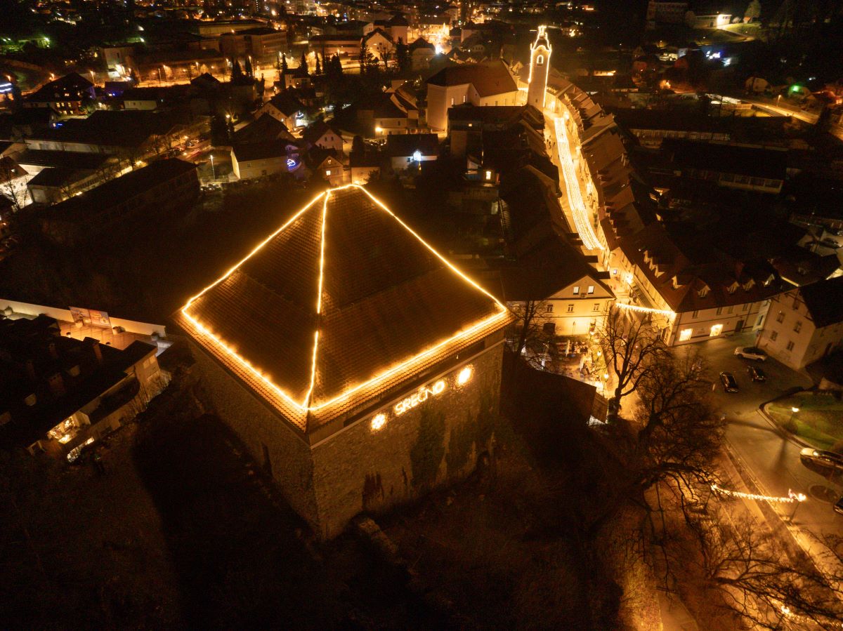 The house roof and city streets are decorated with festive lights.