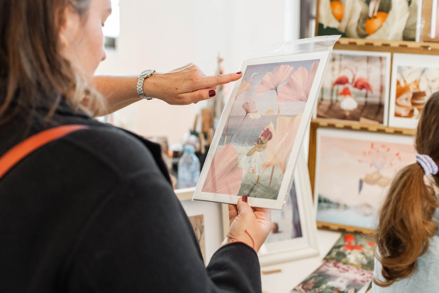 A woman is looking at a framed artwork in gentle pastel colors.