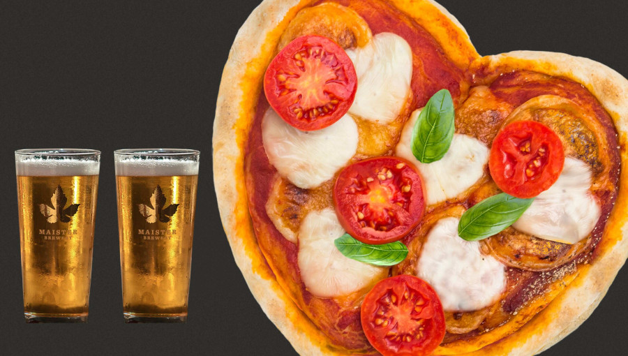 A heart-shaped pizza, topped with mozzarella, fresh tomatoes, and basil, sits against a dark backdrop. To the left, two glasses of beer are placed beside the pizza.