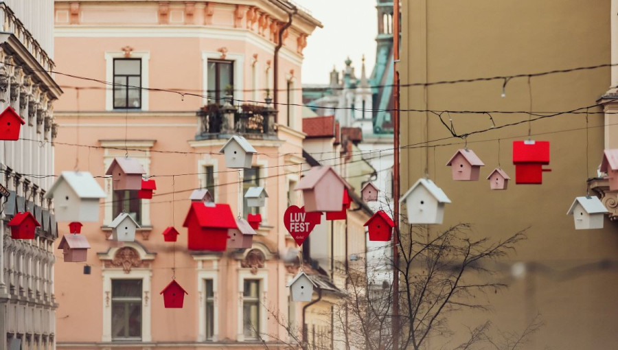 Bele, roza in rdece pticje hisice obesene na vrvicami razpetimi med hisami v ulici.