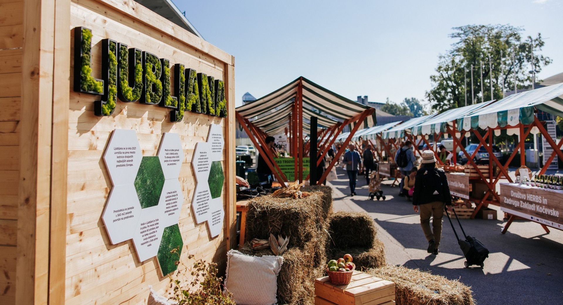 A market with stalls, featuring a prominent green sign that reads "Ljubljana."