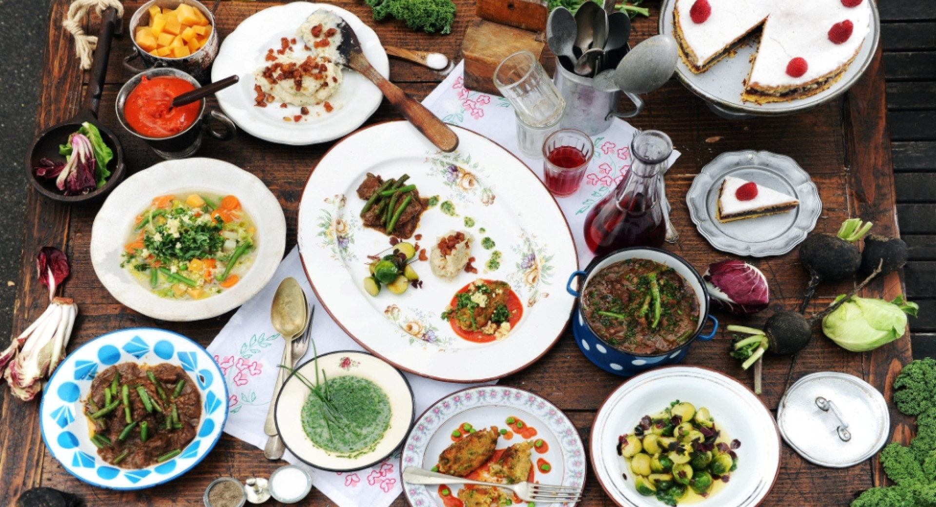 A large number of plates with food on a wooden table.