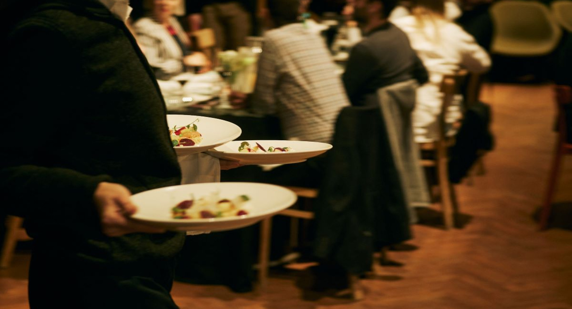 A waiter carries assorted dishes on a plate to the table.