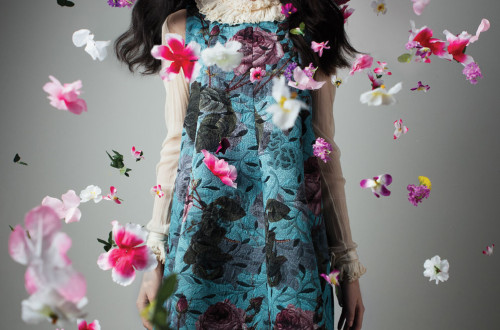 Woman wearing blue dress with flower petals everywhere.