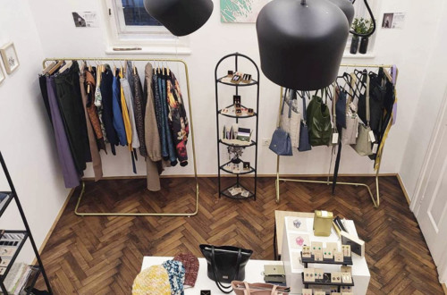 Interior of a store with clothing, bags, and jewelry, lit by lamps and arranged in a modern style.