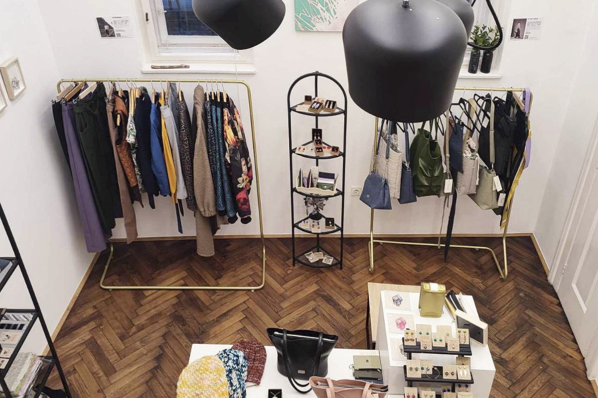 Interior of a store with clothing, bags, and jewelry, lit by lamps and arranged in a modern style.