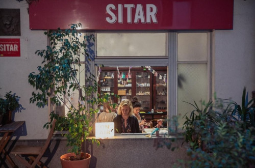 A cozy shop named "Sitar," viewed from the outside, with people inside enjoying the warm atmosphere.