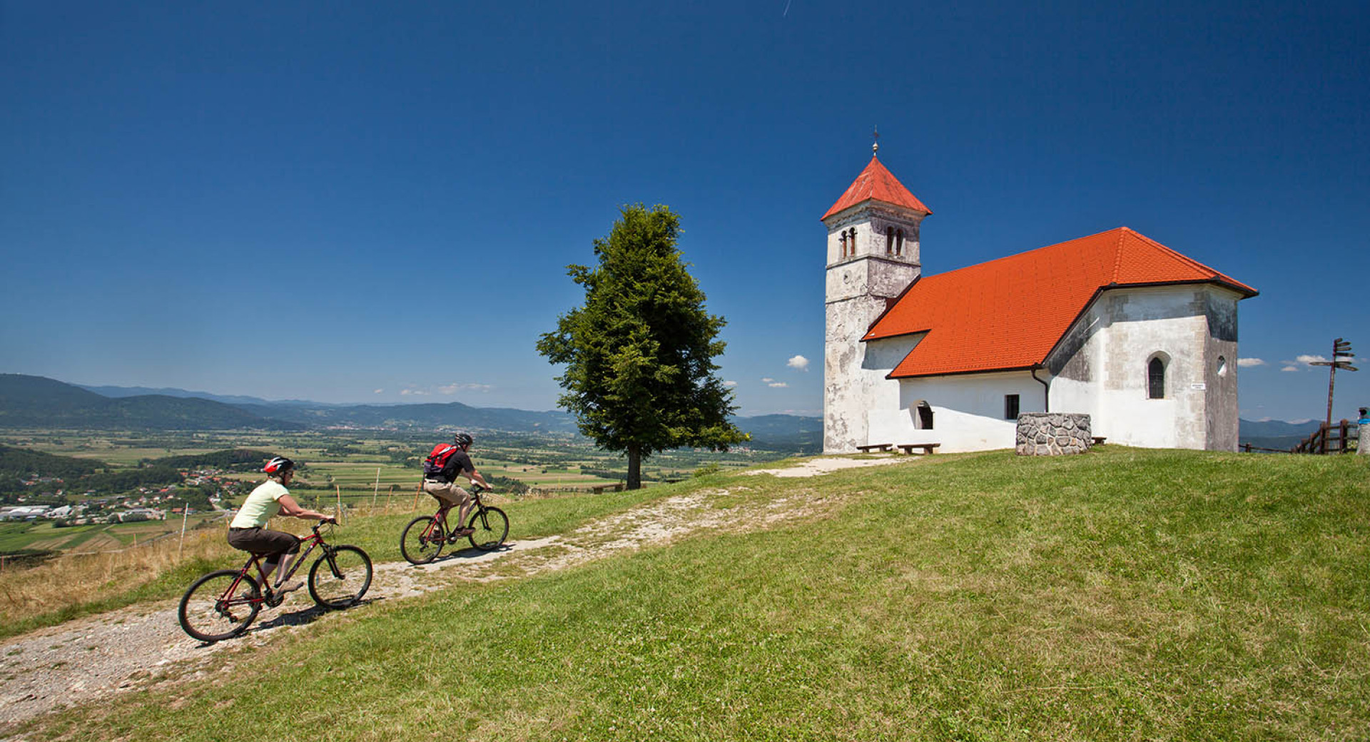 Kolesarja se vzpenjata po hribu do cerkve sv. Ane.