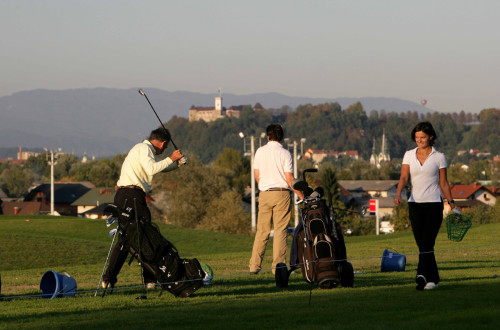 Igralci na igrišču za golf, v ozadju Ljubljanski grad.