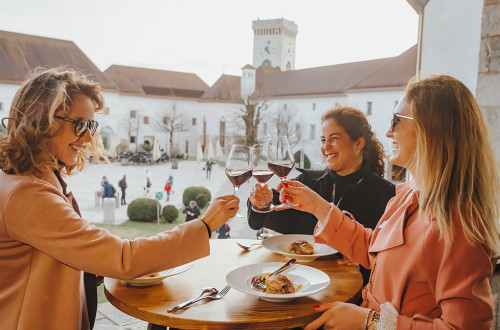 Tri prijateljice na Ljubljanskem gradu azdravljajo s kozarcem vina. 