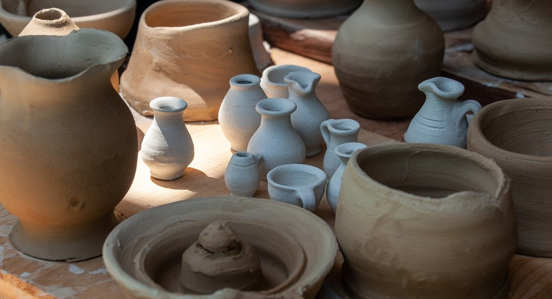 Various pieces of clay ceramics in different shapes and colours, including jugs, vases and bowls.