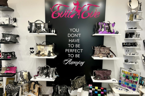 Various handbags and accessories are placed along the wall with a black background. 