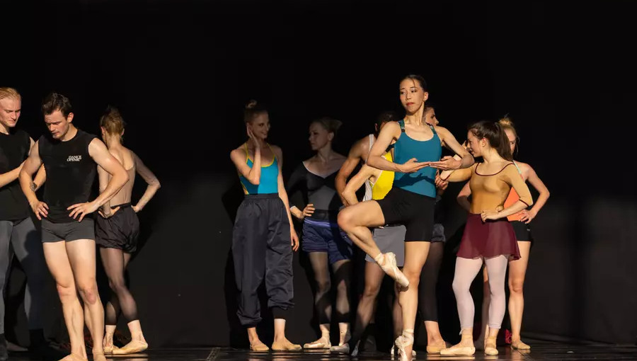 skupina baletnih plesalcev v športnih oblačilih se ogreva na odru