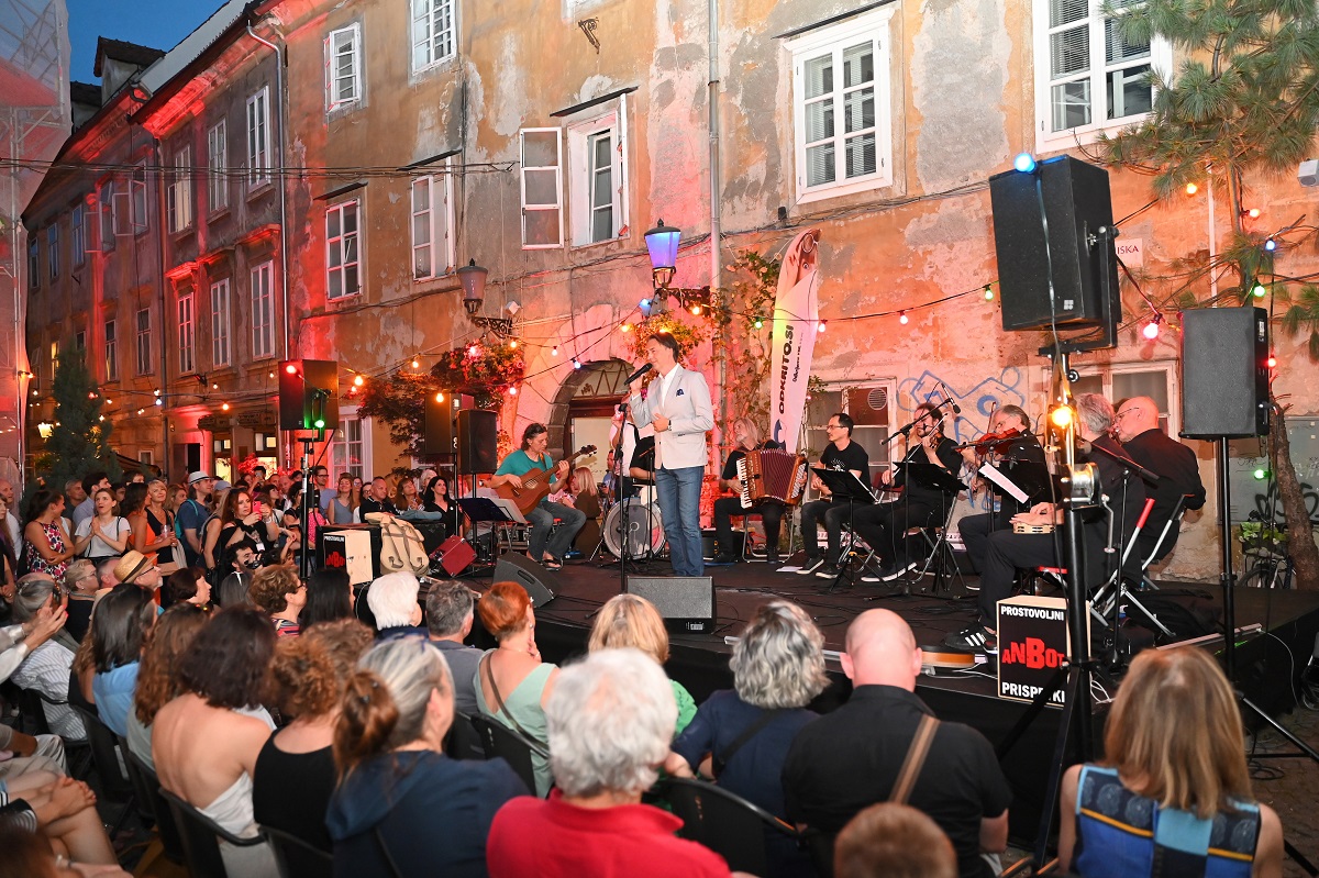 Band performing on stage. A group of people in front. 