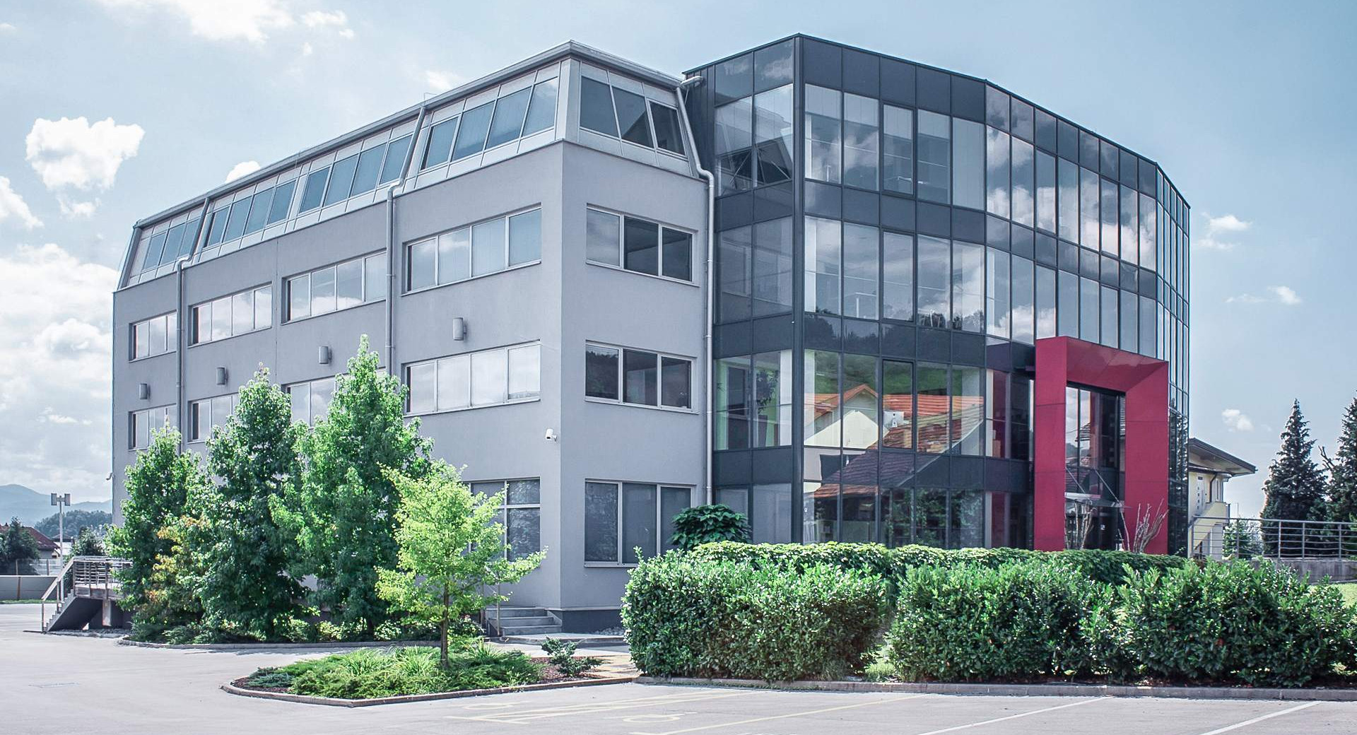 A large gray building with large windows and a red entrance to the building.